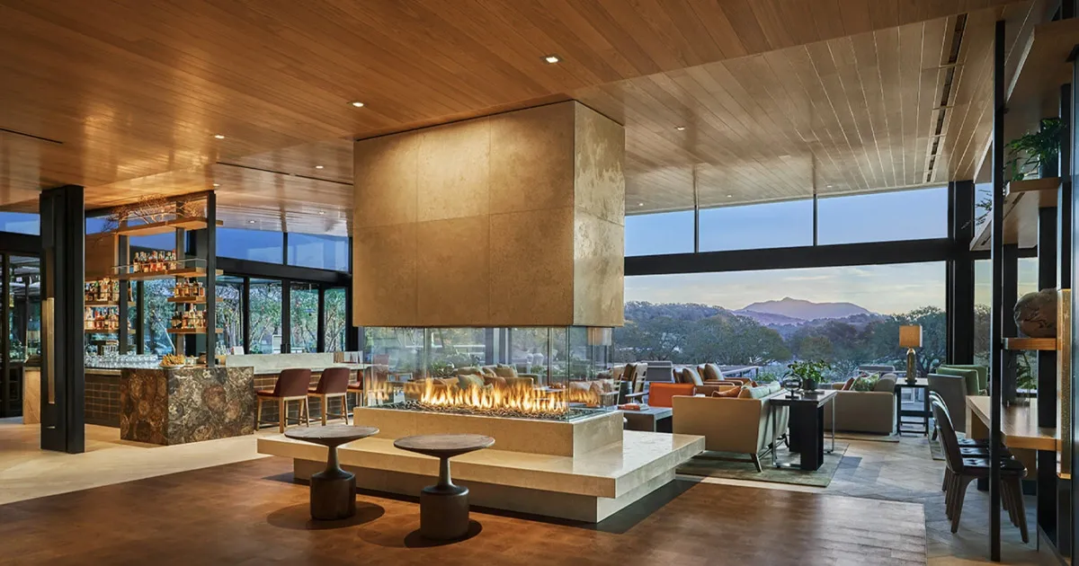 An elegant bar with a square design aesthetic and a large fireplace, and panoramic valley view.
