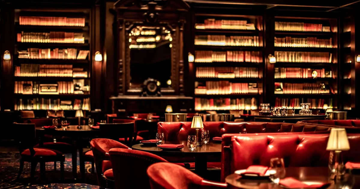 A low-lit hotel lounge with red leather furniture and expansive bookshelves, NoMad, Las Vegas.