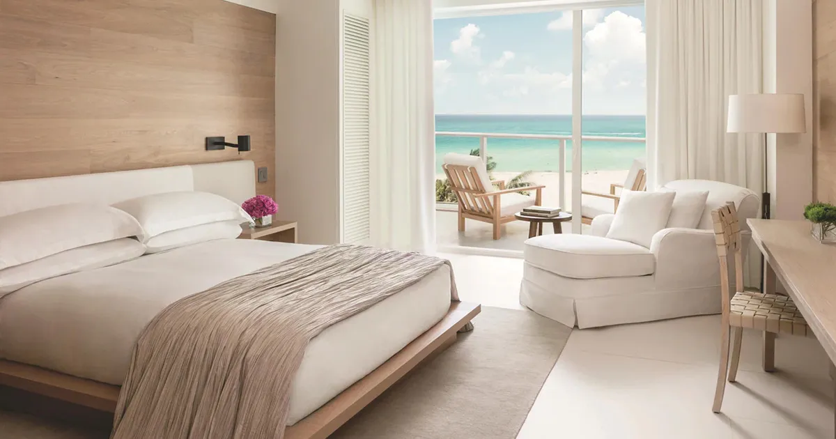 A light and airy hotel bedroom opens up to a beachfront in Miami, The Edition hotel.