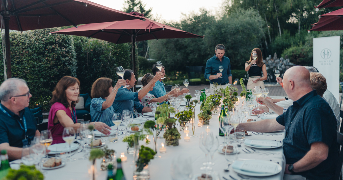 An Ultimate Driving Tours group toasting at a large dining table in an al fresco setting