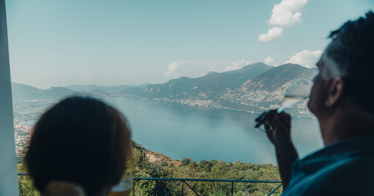 A man and woman toast champagne as they look across Lake Iseo
