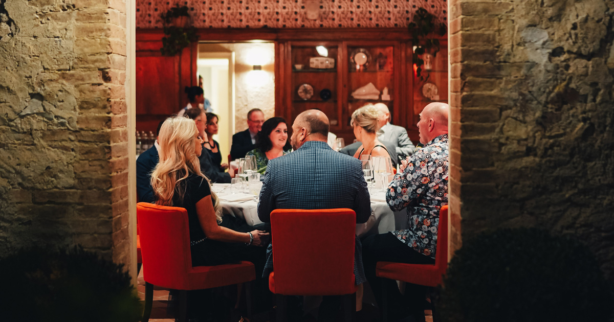 A group of smartly dressed diners enjoying a meal in an elegant room