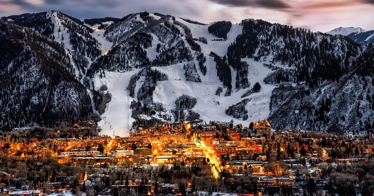 The town of Aspen seen in the evening, brightly illuminated below its famous ski runs. 