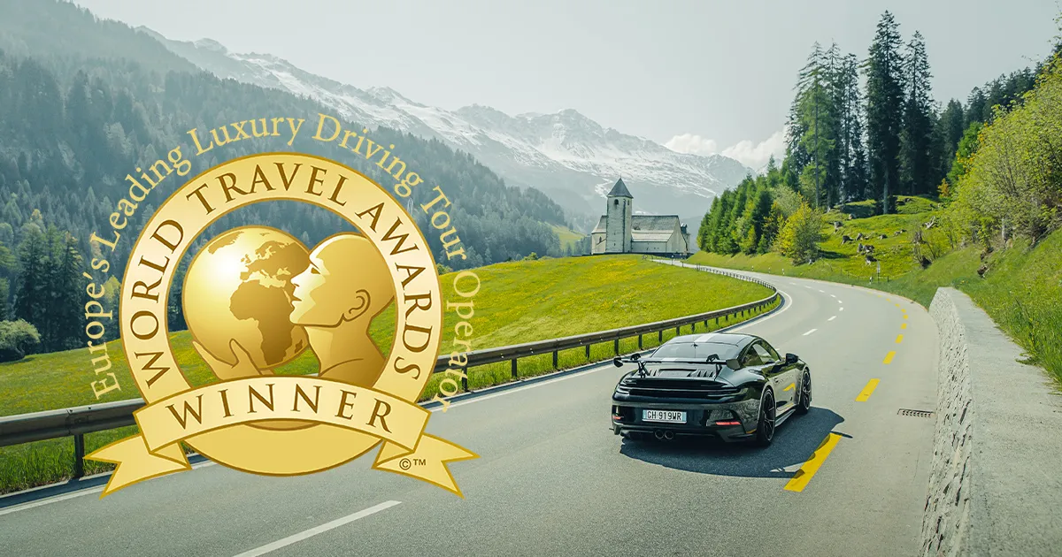A Porsche 911 on a country road overlaid with a graphic showing the World Travel Awards logo