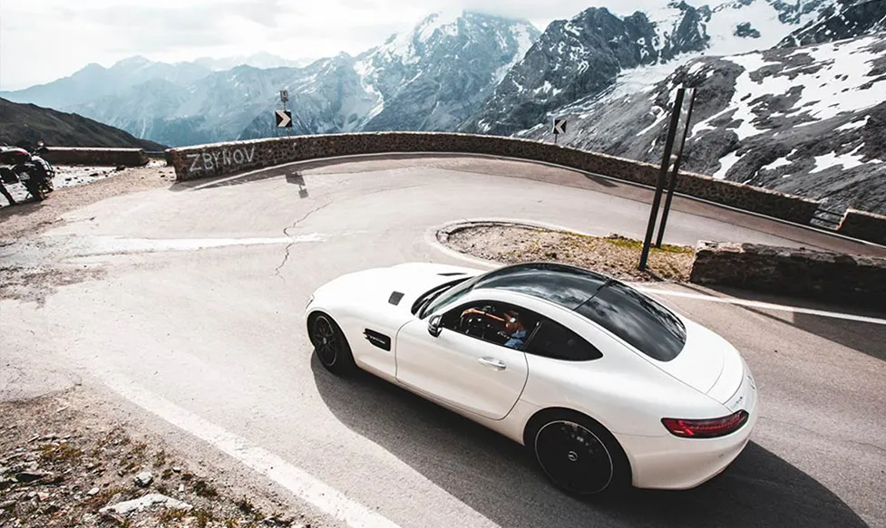 A white Mercedes AMG GTR takes on a hairpin bend during a descent of the iconic Stelvio Pass