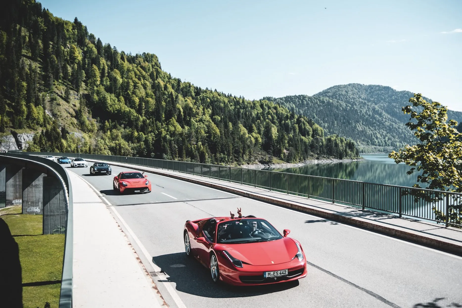 A red Ferrari leads a line of supercars across a bridge in Germany’s Black Forest