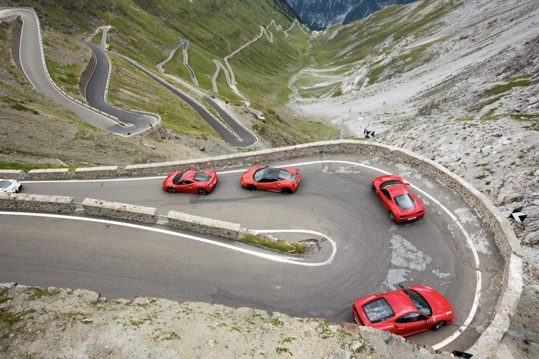 a fleet of Ferraris descend the Stelvio Pass, Italy