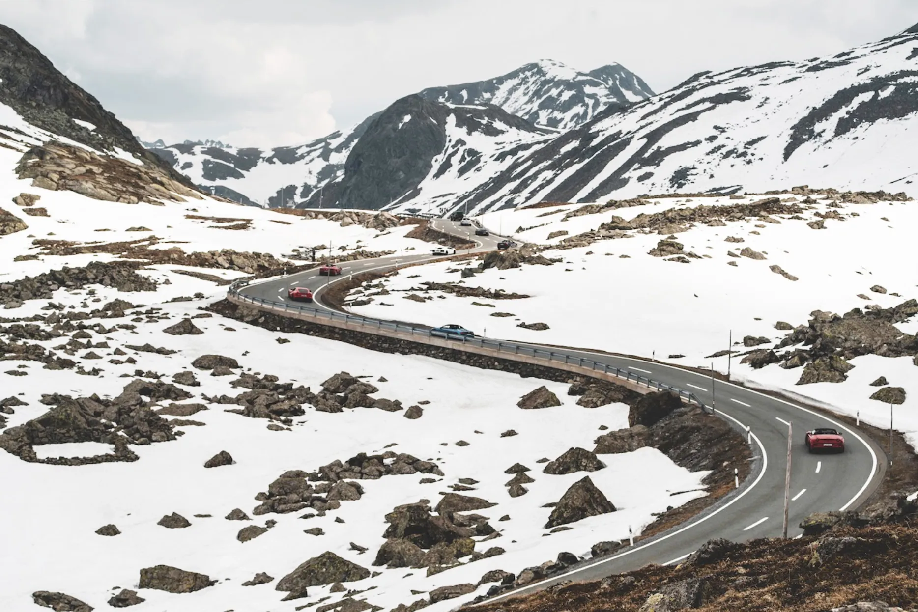 supercars climb the snow-capped Grimsel Pass in Switzerland