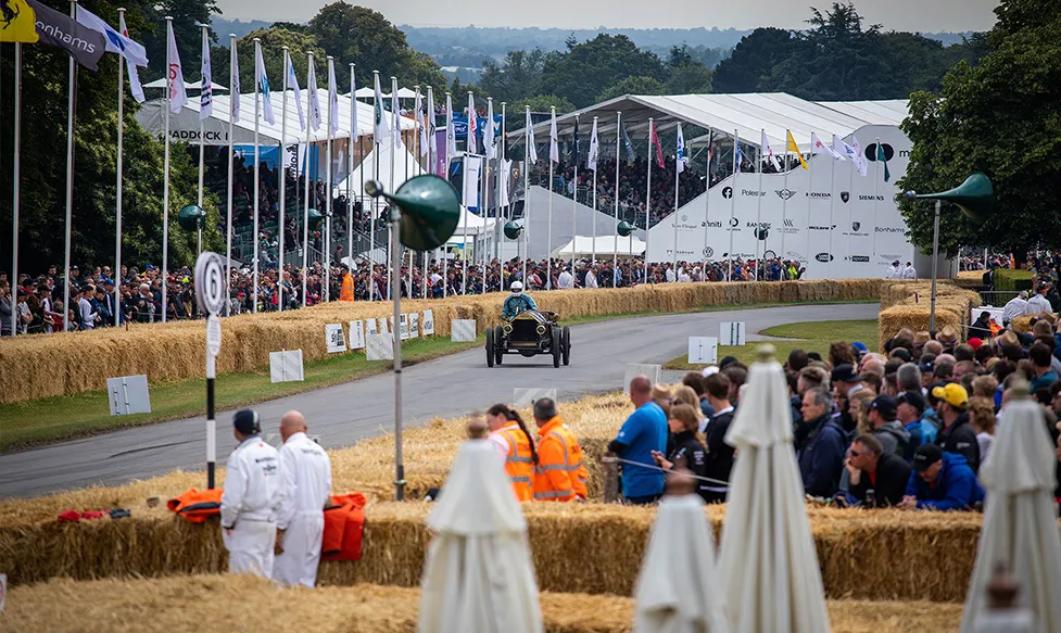 A classic car races up a straight at the Goodwood Festival of Speed as the crowd eagerly watches on