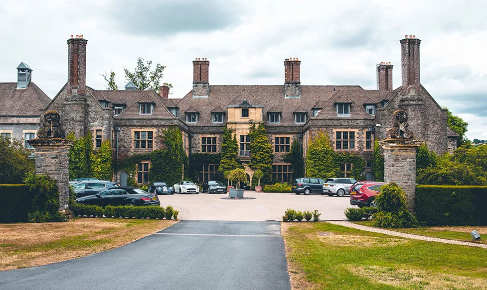 Luxury vehicles sit in the parking area in front of the majestic Llangoed Hall in the Wye Valley, Wales