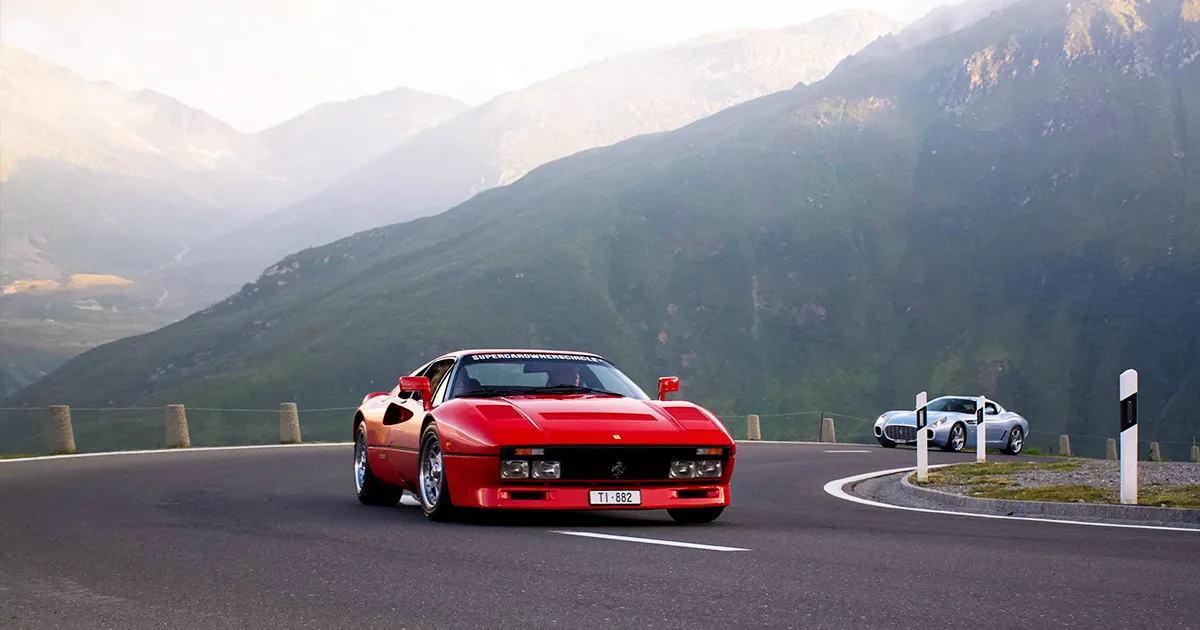 A red Ferrari 288 GTO rounds a corner on a country road