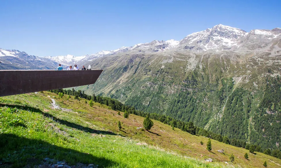 Ultimate Driving Tours guests stand on a viewing station in the Italian Alps, overlooking a dramatic valley