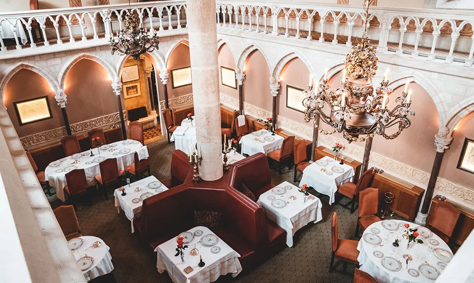 A room full of meticulously prepared tables seen from above as they await guests at the Abbaye de Collonges