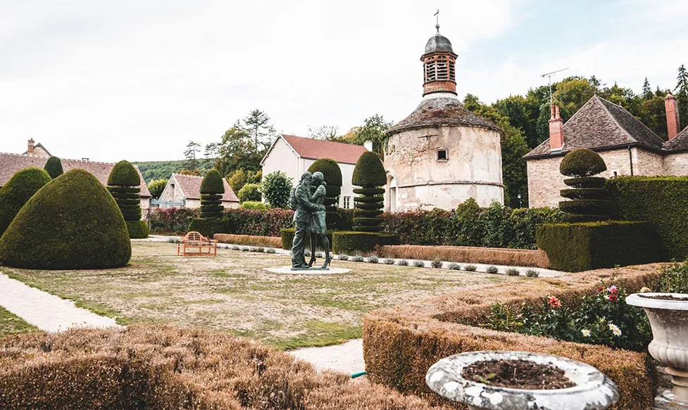 A copper statue of a couple in embrace sits on the middle of the gardens at the Abbaye de Collonges