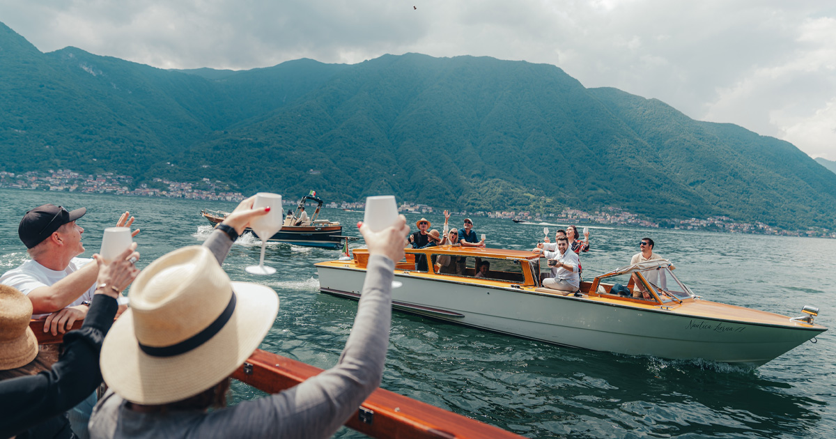 Luxury tour guests on lake boats raise their glasses to toast as they pass by each other