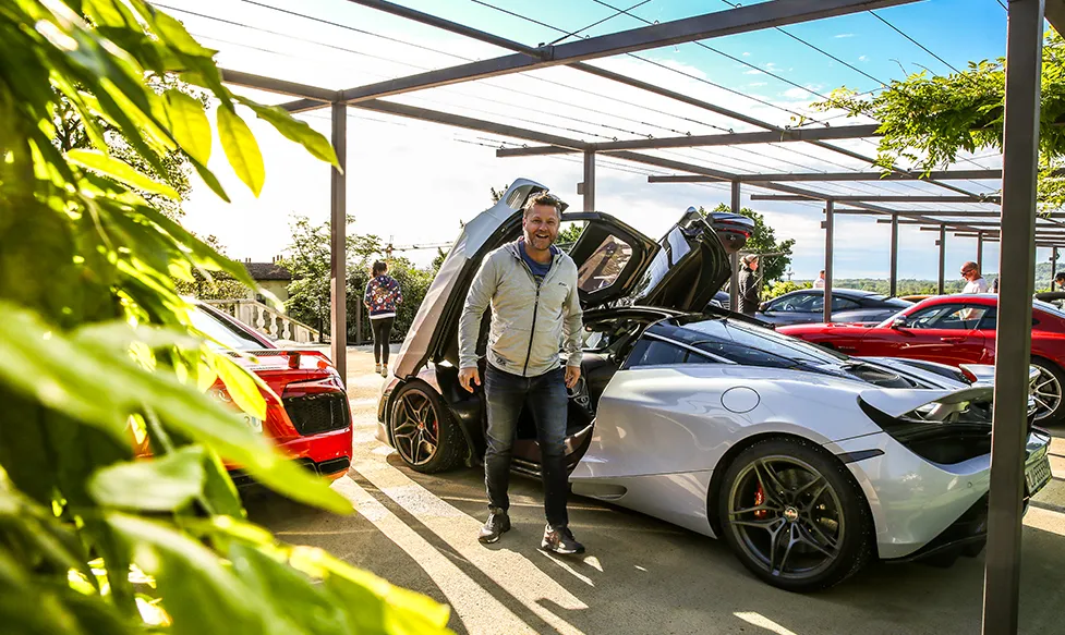A man is filled with happiness as he exits a McLaren 720S on an Ultimate Driving Tours dream car holiday.