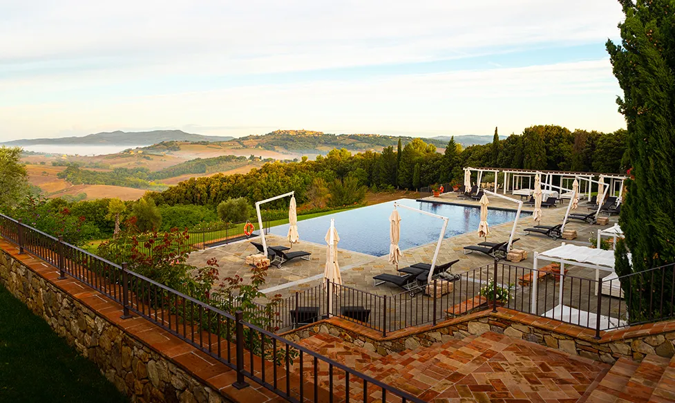 A swimming pool in Tuscany reveals green rolling hills on the Taste of Tuscany luxury tour.
