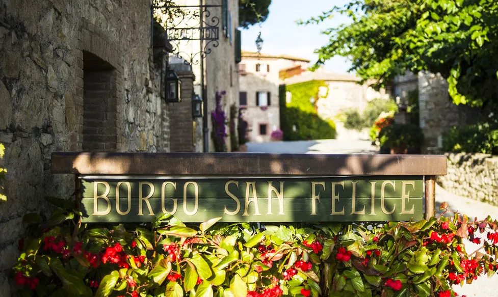 a sun-dappled wooden sign displays the entrance to the five-star hotel in Tuscany, Borgo San Felice