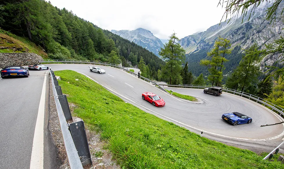 Supercars driving in formation as they navigate a series of hairpin bends descending the Susten pass in Switzerland
