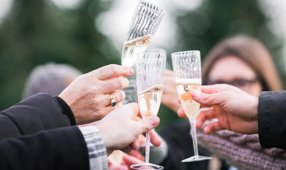 Three champagne flutes are clinked together by friends sharing a toast