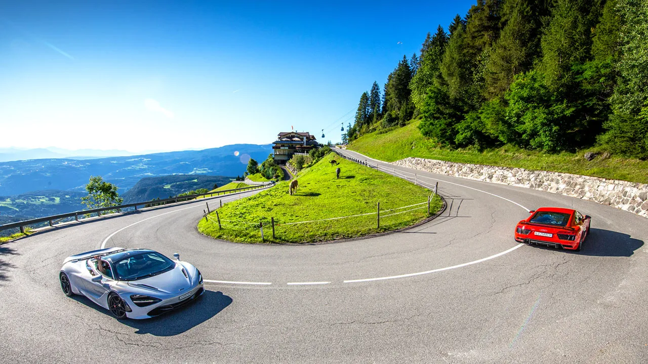 Two supercars navigating their way around a hairpin bend in Switzerland
