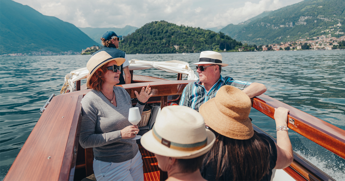 A small group of guests wear sun hats as they enjoy a boat tour on a stunning European lake