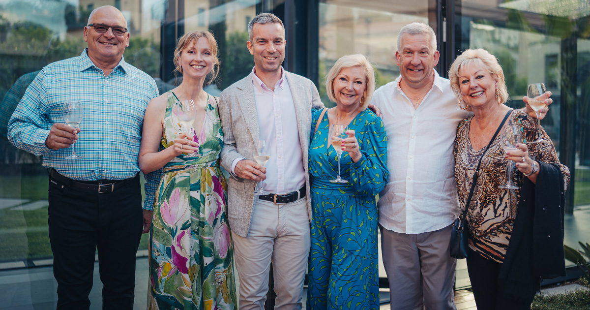 Six European tour guests toasting wine glasses in stylish outfits
