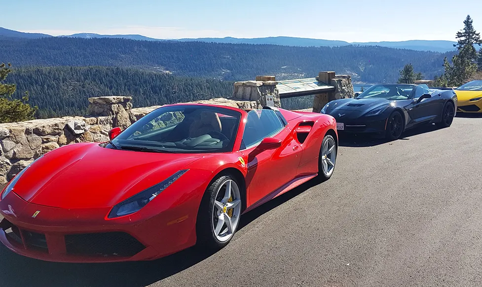 A red Ferrari convertible sits with a black Chevrolet Corvette on an Ultimate Driving Tours luxury escape