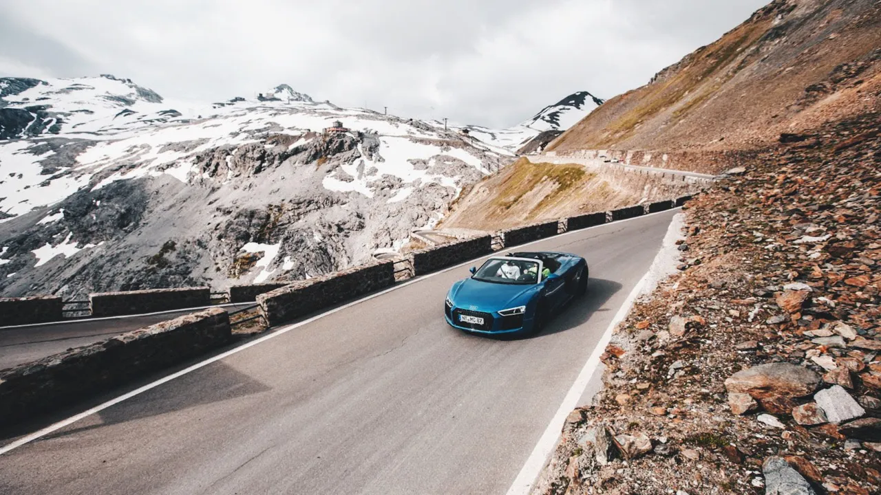 A metallic blue Audi on a straight stretch along Stelvio Pass in Italy