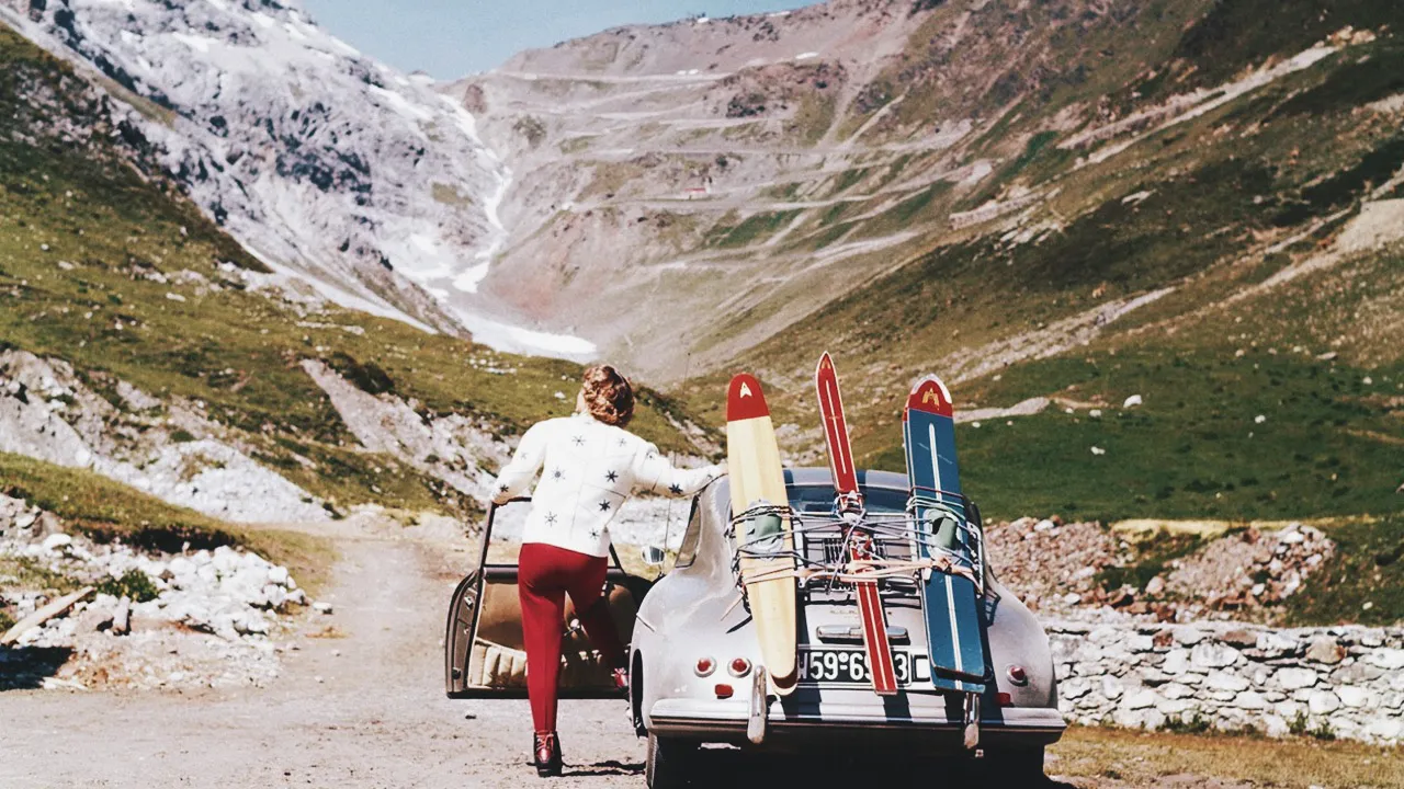 A women, her Porsche and ski equipment pausing to admire Stelvio Pass from its starting point