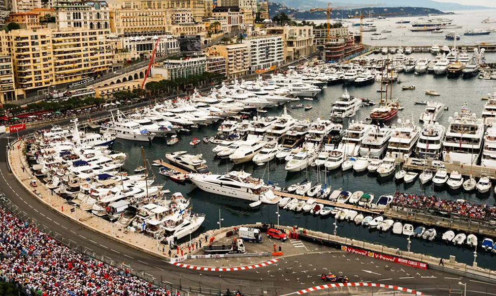 An aerial shot of Port Hercule as it is packed with superyachts and a crowded waterfront in Monte Carlo during the Monaco Grand Prix