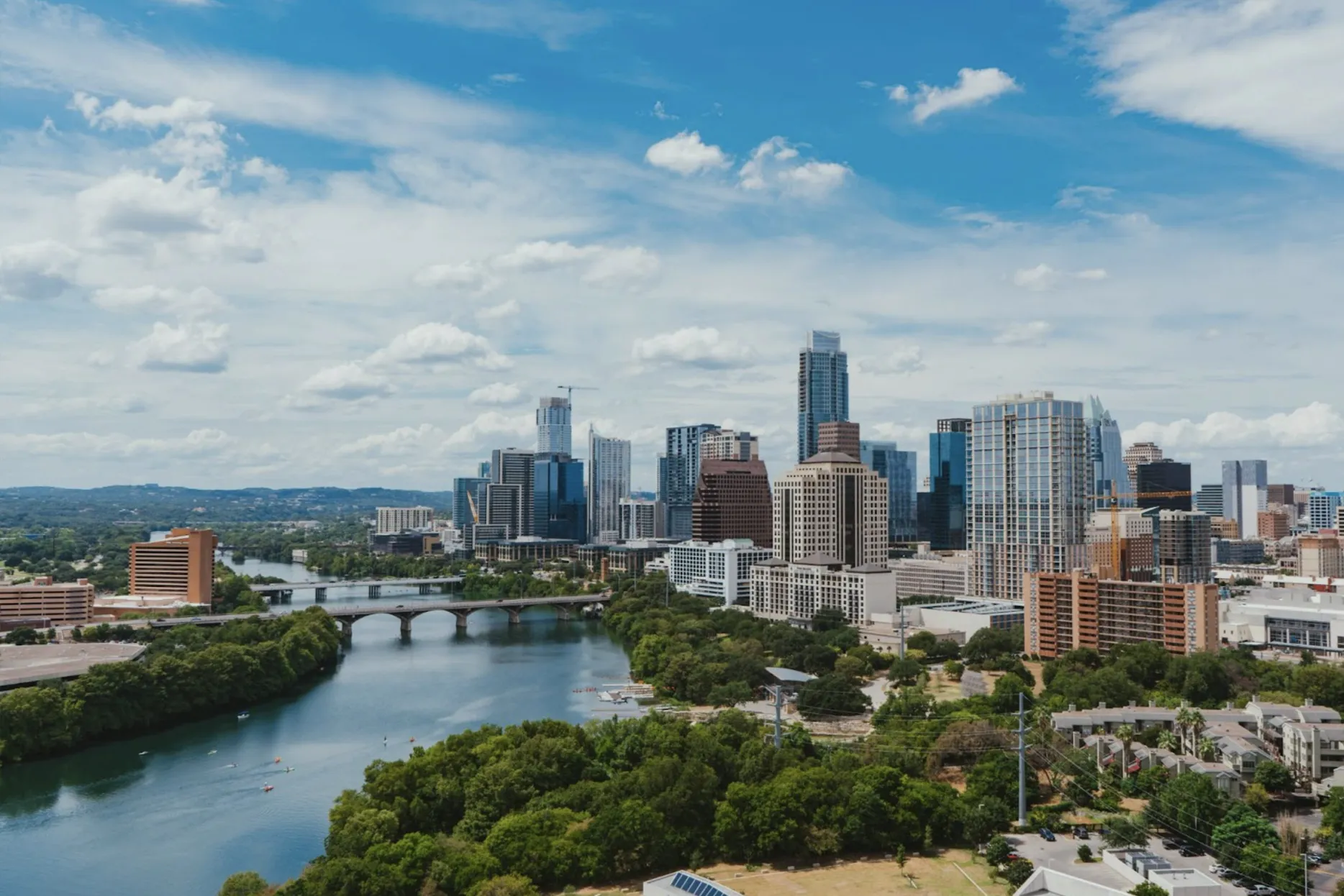 A wide shot of downtown Austin, Texas on a sunny afternoon with the river in the foreground