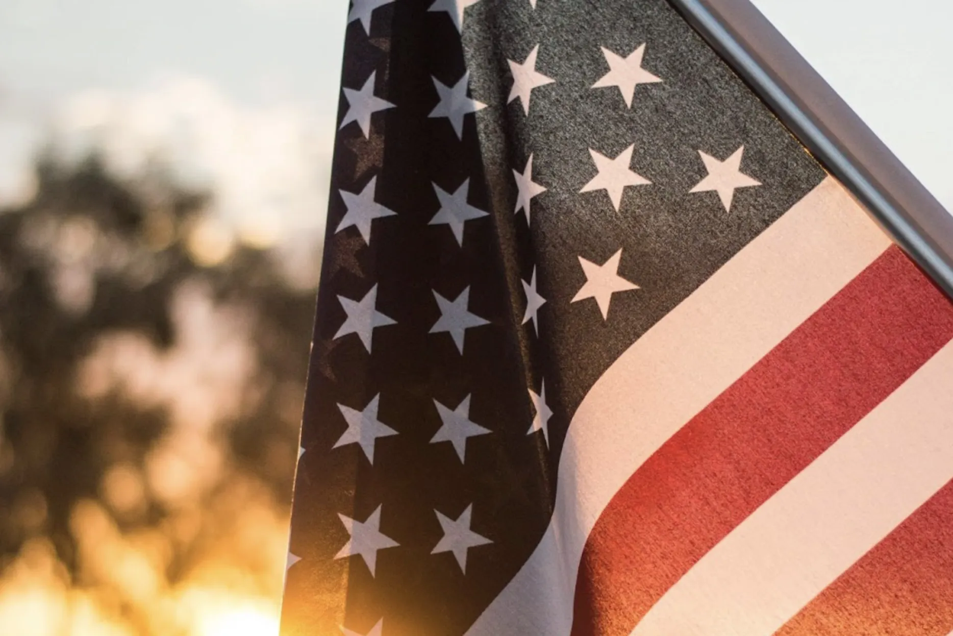 A close up of the American flag with the setting sun behind