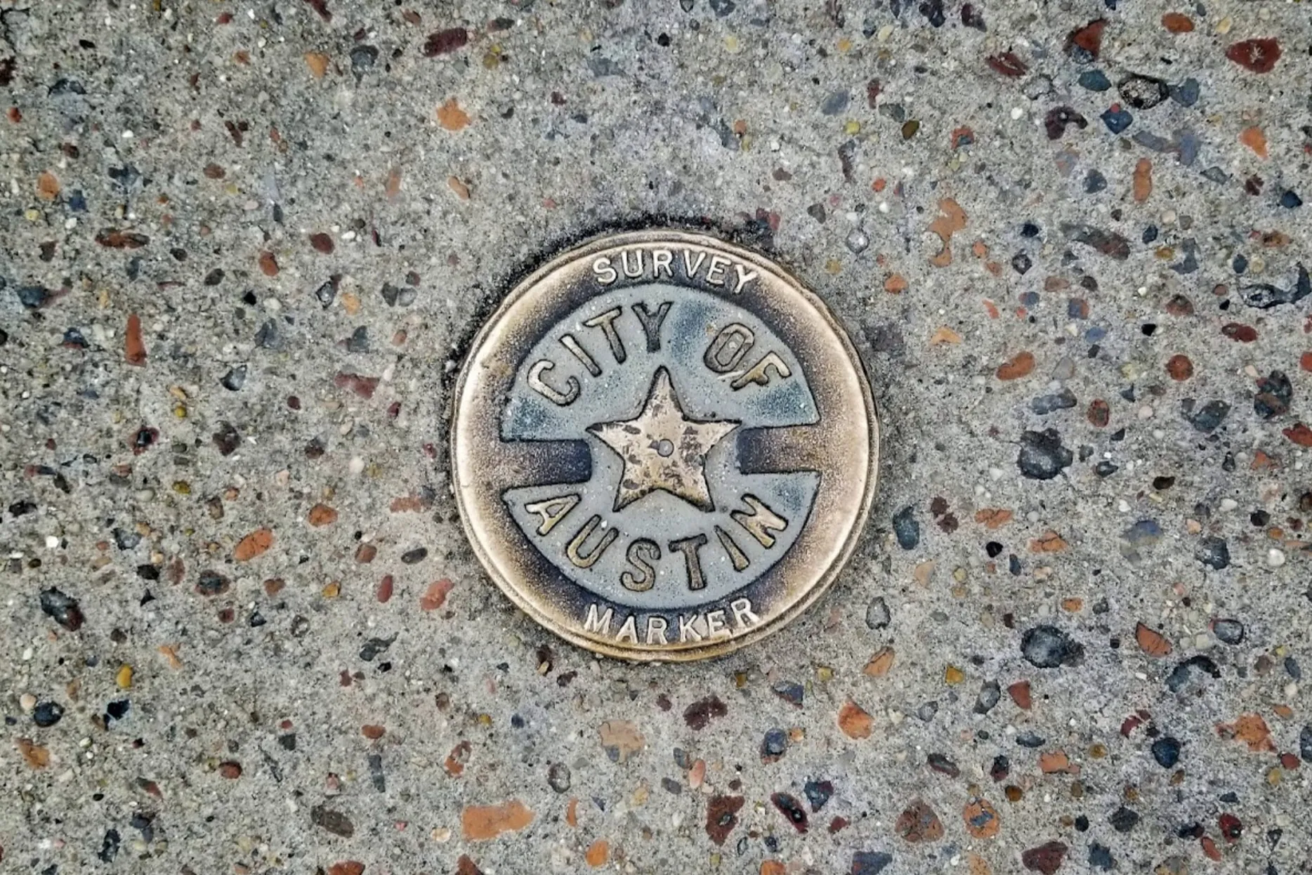 A brass star embedded in the sidewalk as a survey marker in Austin, Texas